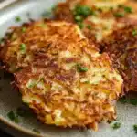 Close-up of crispy vegan potato latkes cooked in an air fryer, served on a white plate.