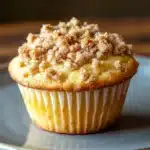 Close-up of a lemon streusel muffin with a crumbly topping and bright lighting.