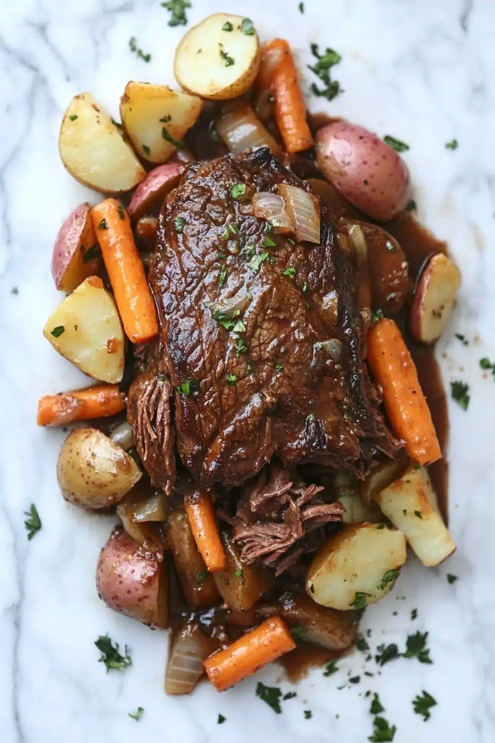 3 packet pot roast slow cooker - the image shows a plate of cooked beef stew with potatoes and carrots. the beef is cooked medium-rare and has a rich, dark brown color. the potatoes are cut into small cubes and are arranged in a pile on top of the beef. the carrots are bright orange and are scattered around the plate. the dish is garnished with chopped parsley. the plate is white and the background is a marble countertop.