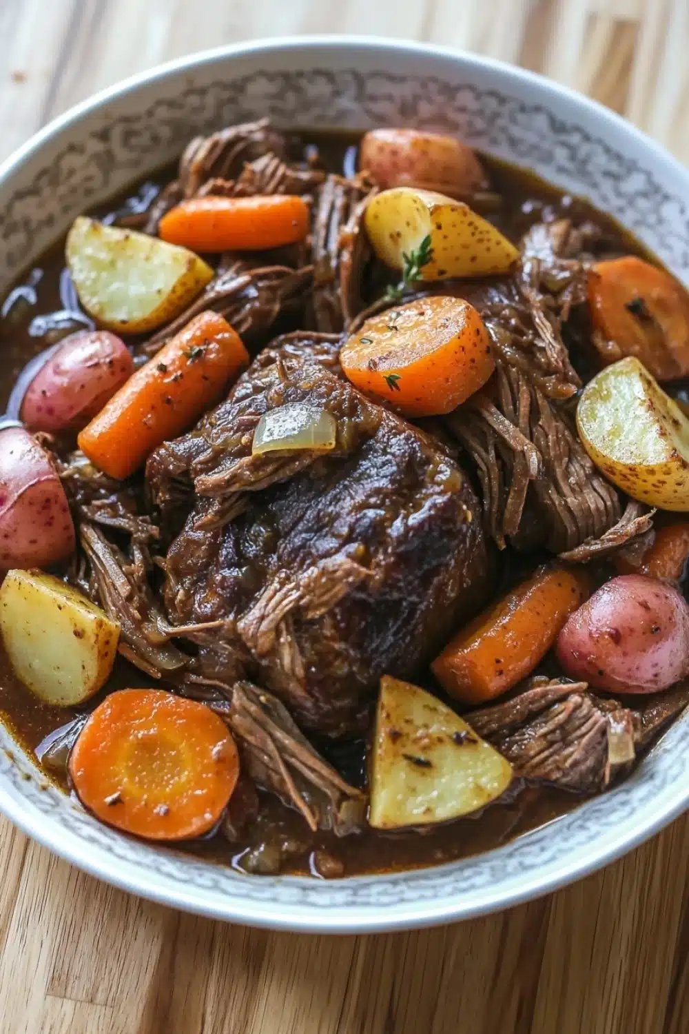 3 packet pot roast slow cooker - the image is a close-up of a bowl of beef stew. the stew is made with chunks of beef, carrots, potatoes, and herbs. the beef is cooked medium-rare and appears to be tender and juicy. the potatoes are cut into small cubes and are arranged in a circular pattern around the beef. the carrots are bright orange and the potatoes are yellow. the herbs are scattered throughout the stew, adding a pop of green color to the dish. the bowl is white with a blue rim and is sitting on a wooden table.