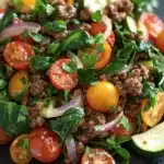 Ground beef dinner low calorie - the image is a close-up of a salad on a black slate plate. the salad is made up of various ingredients, including diced tomatoes, cucumbers, onions, and basil leaves. the tomatoes are bright red and appear to be ripe and juicy, while the cucumbers are sliced and arranged in a circular pattern. the onions are sliced into thin strips and are scattered throughout the salad. the basil leaves are a vibrant green color and add a pop of color to the dish. the overall appearance of the salad is fresh and appetizing.