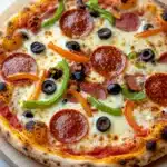 Cast iron pizza on the grill - the image is of a pepperoni pizza on a wooden cutting board. the pizza is round and has a golden brown crust. it is topped with melted cheese, sliced pepperoni, green bell peppers, and black olives. the pepperoni is arranged in a circular pattern, with some overlapping each other. the olives are scattered throughout the pizza, adding a pop of color to the dish. the background is a white wooden table.