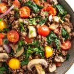 Ground beef for dinner main dishes - the image is a close-up of a bowl of food. the bowl is made of dark brown ceramic and is placed on a white marble countertop. the food appears to be a salad with a variety of ingredients, including diced tomatoes, sliced mushrooms, red onions, and green leafy vegetables. the tomatoes are bright red and appear to be ripe and juicy, while the mushrooms are sliced and have a light brown color. the greens are a mix of green and red, and they are scattered throughout the dish. the dish looks fresh and appetizing.