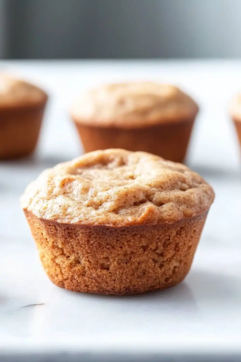 Protein muffin with almond flour - the image shows a group of freshly baked muffins on a white surface. the muffins are golden brown in color and have a crumbly texture on top. they are arranged in a row, with the largest muffin in the foreground and the others in the background. the background is blurred, but it appears to be a kitchen countertop. the overall mood of the image is warm and inviting.