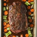 Slow cooker roast beef from frozen - the image shows a rectangular baking dish with a large piece of cooked meat in the center. the meat appears to be a medium-rare ribeye steak, with a dark brown crust on top. it is surrounded by a bed of sliced carrots and celery. the carrots are bright orange and appear to be cooked until they are soft and tender. the celery is a bright green color and is arranged in a circular pattern around the meat. the dish is sitting on a white countertop.
