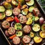 Trader joes chicken sausage sheet pan - the image shows a rectangular baking tray filled with a variety of vegetables. the vegetables include zucchini, red onions, and yellow bell peppers. the tray is garnished with chopped parsley. the background is a dark wooden table with a white napkin on the side. the overall color palette of the image is warm and inviting.