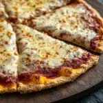 King arthur gluten free pizza crust - the image shows a freshly baked pizza on a wooden cutting board. the pizza has a golden brown crust and is topped with melted cheese and tomato sauce. the cheese is melted and bubbly, and the tomato sauce is a deep red color. the cutting board is placed on a dark grey countertop. the background is blurred, making the pizza the focal point of the image.