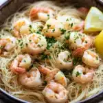 Olive garden shrimp scampi with angel hair pasta - the image shows a bowl of spaghetti with shrimp and lemon wedges. the spaghetti is cooked al dente and is garnished with chopped parsley. the shrimp are pink and appear to be cooked medium-sized. the bowl is made of dark brown ceramic and is sitting on a white tablecloth. there are two lemons on the side of the bowl, one on each side. the background is blurred, but it appears to be a kitchen countertop.