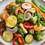 Sauteed vegetables in sauce - the image is a close-up of a colorful salad in a bowl. the salad is made up of various vegetables, including broccoli, red bell peppers, sliced cucumbers, and red onions. the vegetables are arranged in a circular pattern on a white plate with a speckled pattern. the colors of the vegetables are vibrant and the dish looks fresh and appetizing. the bowl is sitting on a wooden table.