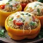 Stuffed bell peppers ricotta - the image shows four stuffed bell peppers on a brown plate. the bell peppers are yellow in color and have a quinoa-like texture. they are topped with melted cheese and fresh basil leaves. the plate is garnished with a sprig of parsley. the background is dark and out of focus, making the bell peppers the focal point of the image.