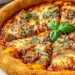 Deep dish pizza tattoo - the image is of a freshly baked pizza on a wooden cutting board. the pizza has a golden brown crust and is topped with melted cheese, tomato sauce, and chunks of meatballs. there are also fresh basil leaves scattered on top of the pizza. the background is blurred, but it appears to be a kitchen countertop with a white cloth napkin and a wooden spoon.